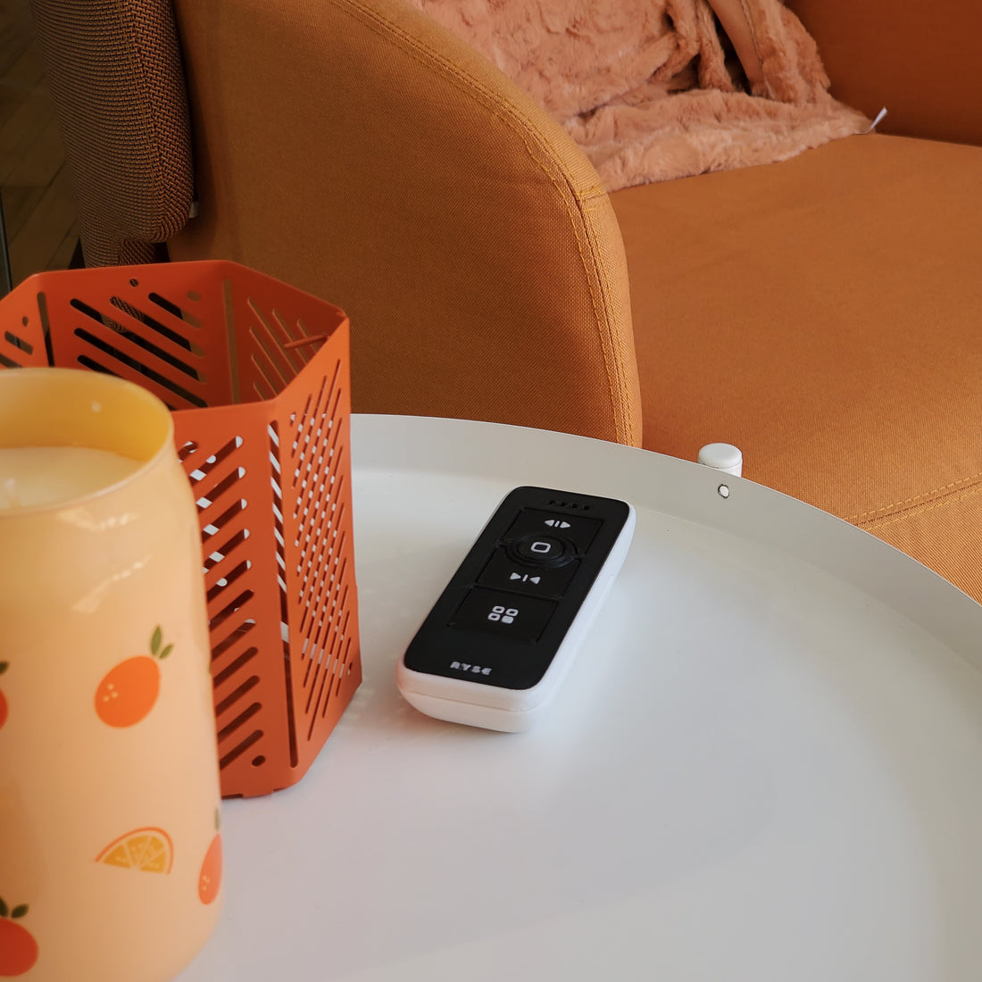 White electronic device with digital display on a white surface next to an orange metal stand and a pink cushion.
